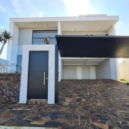 Fachada moderna de uma residência em Lajeado, Brasil, com revestimento branco e área externa pavimentada.