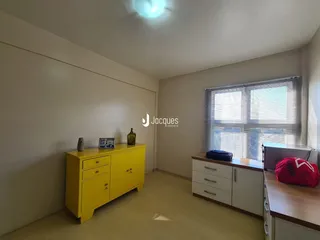 Ambiente interno de uma sala com móveis amarelos e janela.