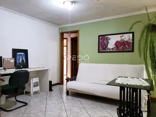 Sala de estar com sofá branco e piso de cerâmica em Lajeado.