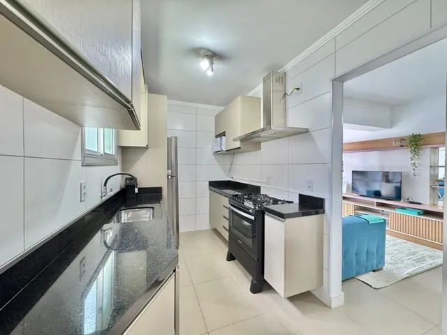 Cozinha moderna com bancadas escuras e revestimento branco.