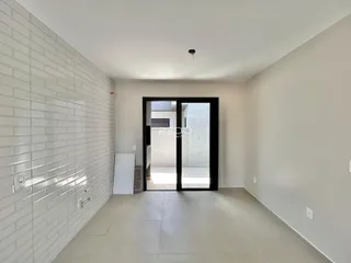 Hall de entrada com parede de tijolos brancos e piso de cerâmica clara.
