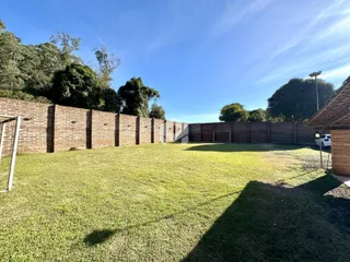 Vista de um quintal gramado com muro de tijolos.