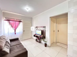 Sala de estar com sofá e janela com cortinas vermelhas.