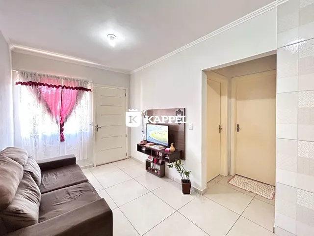 Sala de estar com sofá e janela com cortinas vermelhas.