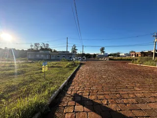 Vista externa de uma propriedade com terreno gramado e uma estrada de paralelepípedos.