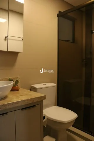 Foto de um banheiro interno com vaso sanitário e paredes em tom neutro.
