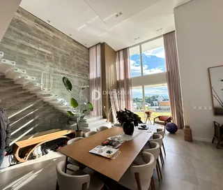 Interior de uma sala de estar com grande janela e escadaria em um imóvel no Brasil.