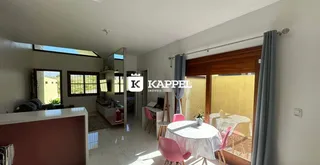 Uma sala de jantar com mesa redonda e cadeiras rosa em um ambiente claro.