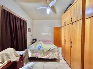 Quarto com armário de madeira e cortinas escuras.
