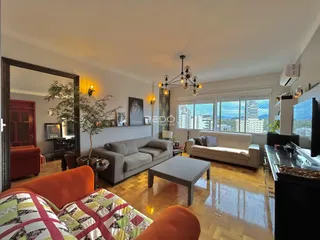 Sala de estar com piso de madeira e grande janela.
