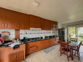 Vista interna de uma cozinha com armários de madeira e mesa de jantar em Lajeado.