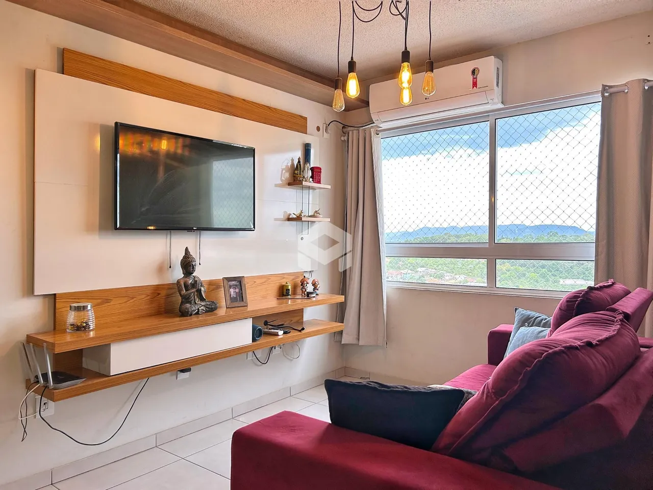 Sala de estar com televisão e janela com vista para a paisagem.