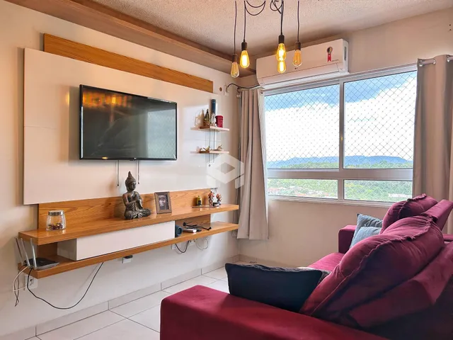 Sala de estar com televisão e janela com vista para a paisagem.
