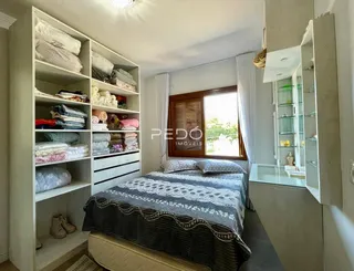 Quarto com estantes brancas e cama de casal.