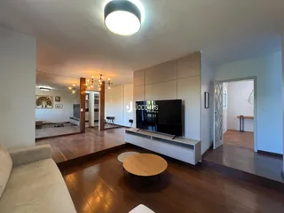 Sala de estar com piso de madeira e sofá claro.