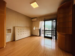 Quarto com piso de madeira e armário em um ambiente claro.