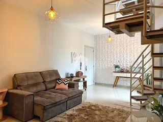 Sala de estar com sofá e escadaria em ambiente claro.