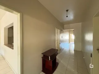 Hall de corredor interno com piso cerâmico claro.