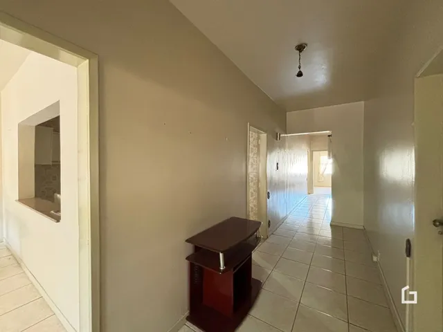 Hall de corredor interno com piso cerâmico claro.