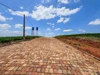 Vista de uma estrada pavimentada que se estende por uma paisagem rural sob um céu azul.