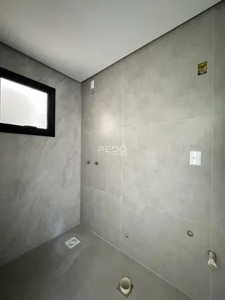 Foto do interior de um banheiro com paredes cinzas e piso de concreto.