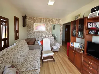 Sala de estar com sofá e piso de madeira em uma residência.