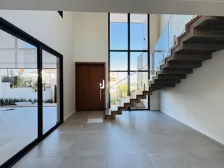 Ambiente interno de uma área de transição com grandes portas de vidro e escadaria em Lajeado.