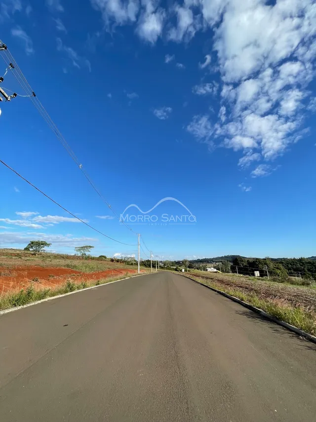 Vista de uma estrada asfaltada sob um céu azul com nuvens.