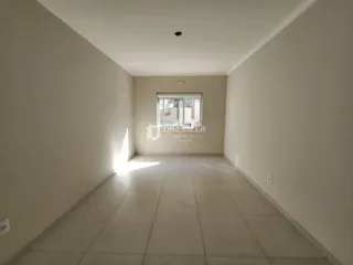 Hall de corredor com paredes brancas e piso de cerâmica claro.