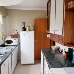 Uma cozinha com armários brancos e bancadas escuras é visível na propriedade.