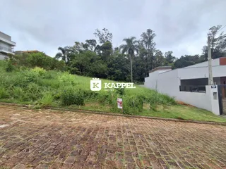 Vista externa de uma propriedade com paisagismo e área pavimentada.