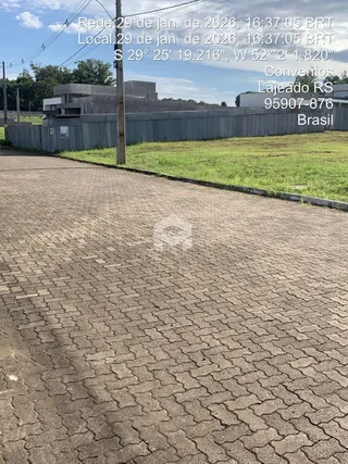 Vista externa do terreno com cerca de madeira e pavimento de tijolos.