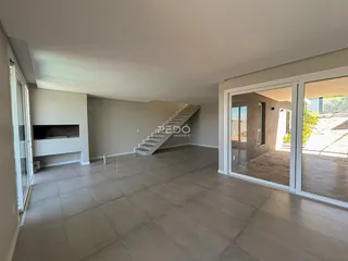 Ambiente interno de uma sala ampla com piso claro e escadaria.