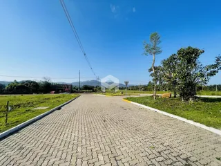 Vista da entrada de uma propriedade com paisagem verde e estrada pavimentada.