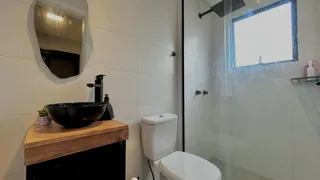 Foto de um banheiro com bancada de madeira e box de vidro transparente.