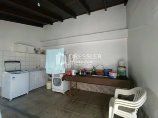 Foto interna de uma cozinha com armários brancos e piso de concreto.