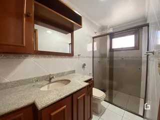 Foto de um banheiro com bancada e box de vidro.
