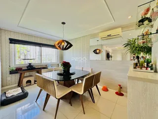 Sala de jantar com mesa de vidro e cadeiras de madeira clara em um imóvel no Brasil.
