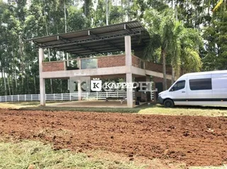 Fachada de uma residência com estrutura de concreto e área de terra no primeiro plano.