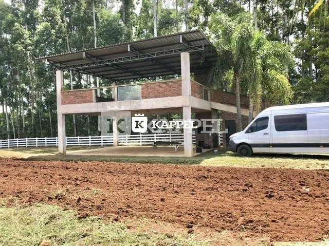 Fachada de uma residência com estrutura de concreto e área de terra no primeiro plano.