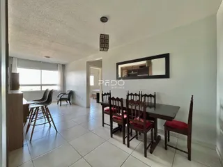 Sala de jantar com mesa de madeira e janela em um imóvel no Brasil.