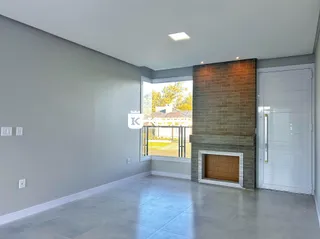 Uma sala ampla com piso de concreto e uma parede de tijolos exposta.