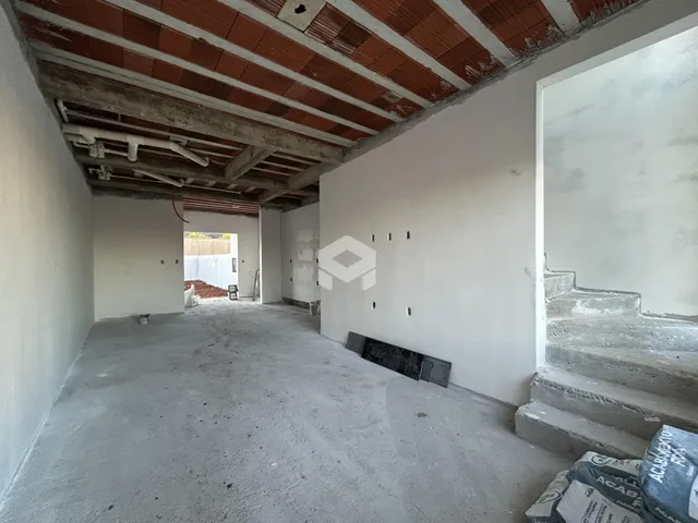 Vista interna de um espaço com piso de concreto e teto exposto.