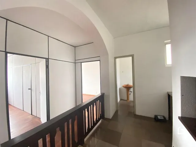 Hall de entrada com piso de madeira e grade escura.