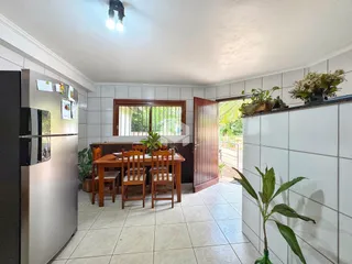 Interior de uma sala de jantar com mesa de madeira e piso de cerâmica.