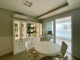 Uma sala de jantar com mesa redonda e armários brancos.