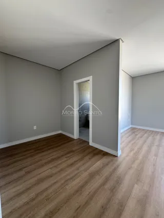 Vista interna de um cômodo com piso de madeira clara e paredes cinza.