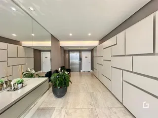 Corredor interno com revestimento de painéis brancos e piso claro.