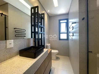 Banheiro moderno com revestimento cerâmico e bancada escura.