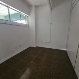 Vista de um corredor interno com paredes brancas e piso escuro.